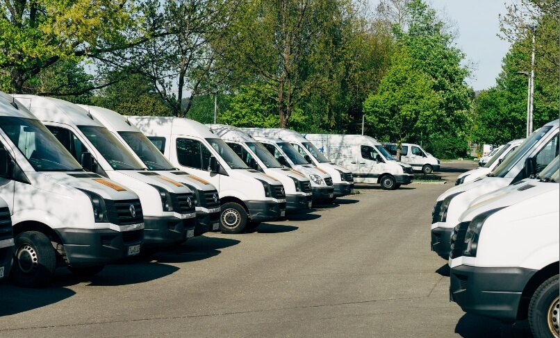 Parking lot of Custom Staffing's fleet of white vans for transportation